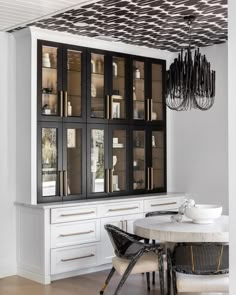 the dining room table is surrounded by black and white china cabinets