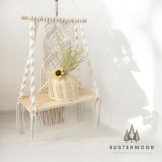 a white macrame hanging from a rope with a plant in it and some other items on the shelf