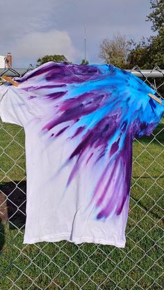 a t - shirt is hanging on a wire fence in front of a grassy field