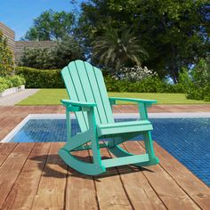 a green rocking chair sitting on top of a wooden deck next to a swimming pool