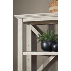 two black vases are on top of a white shelf with a plant in it