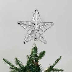 an ornament shaped like a star hanging from the top of a christmas tree