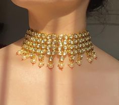 Adorn your beautiful personality with this exquisitely designed and handcrafted high quality kundan choker necklace and earrings set . Pair it up with your silks and satins and shine like a glowing star at the next event!Necklace weight 120 GM's Length of the metal part 7 inches with an adjustable zari thread at the backWidth from top to bottom 2.5 inchesEarrings length 2.2 inchesWeight 24 GM'sColour:Emerald Green******************************************Product Care: Avoid spraying perfume or d Gold Kundan Choker With Gota Work, Festive Gold Choker With Gota Work, Festive Gold Gota Work Choker, Festive Kundan Choker Necklace, Party Kundan Necklace With Gota Work In Temple Style, Kundan Necklace With Mirror Work For Celebration, Gold Kundan Bollywood Choker, Temple Jewelry Kundan Chandbali Choker, Festive Kundan Choker For Ceremonial Occasions