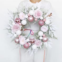 a person holding a wreath with pink and white ornaments