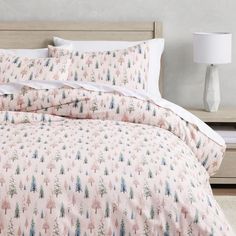 a bed with pink and blue trees printed on the comforter, along with two lamps