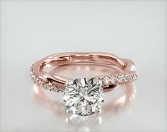 a rose gold engagement ring with a round diamond in the center and side stones on each band