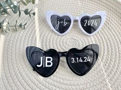 two heart shaped sunglasses sitting on top of a white rug next to a plant with leaves