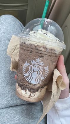 a person holding up a starbucks drink in their hand while sitting on a car seat