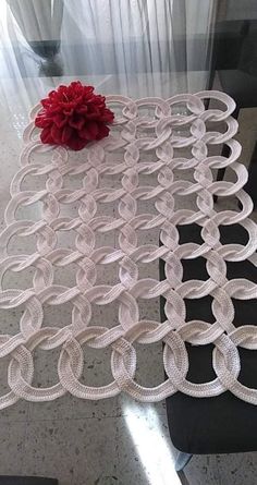 a glass table with a red flower sitting on it's side and some white circles around the edge