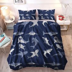 a bed covered in blue and white sharks on it's side, with two lamps next to the headboard