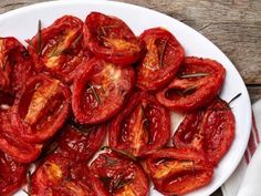 a white plate topped with sliced up tomatoes on top of a wooden table next to a napkin