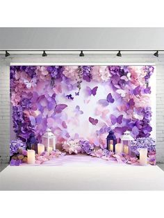 purple flowers and butterflies are on the backdrop for a photo shoot in front of a white brick wall