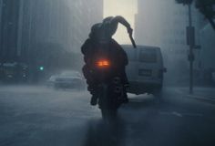 a person riding a motorcycle on a city street in the rain with their headlight turned red