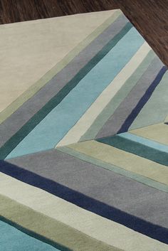 an area rug with multiple colored stripes on the top and bottom, along with a wooden floor