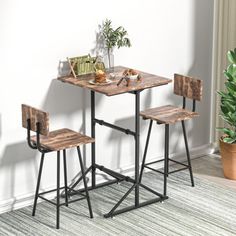 a small table with two stools next to it and a potted plant in the corner