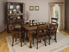 a dining room table and chairs with apples on the wooden top, in front of an open bookcase