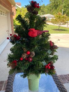 a christmas tree made out of pine cones and red berries is sitting on a table