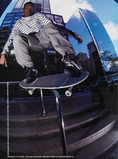 a man riding a skateboard up the side of a metal rail in front of a tall building