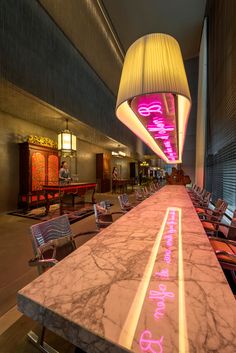 a long table with pink lights on it in a room filled with chairs and tables