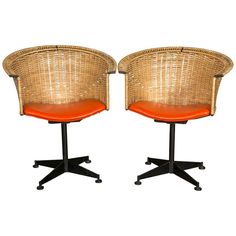 a pair of chairs with orange cushions on each side and black legs, sitting next to each other in front of a white background