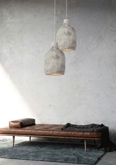 a brown leather couch sitting in front of two hanging light bulbs on a white wall