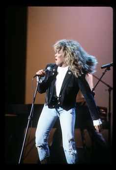 a woman standing in front of a microphone on stage