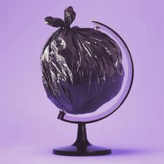 a purple trash bag sitting on top of a black metal stand in front of a purple background