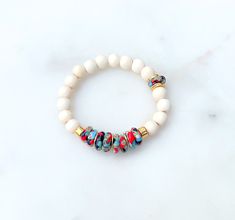 "♥ PLEASE NOTE Runs a little small. I typically wear a size 7 inch bracelet but prefer the 6 3/4 size in this bracelet. Please size accordingly  ♥ THIS BRACELET FEATURES Creamy White Wood 8mm Gold Mykonos Beads 6mm Multicolored Krobo Glass  Brushed Gold Discs ♥ FIND YOUR PERFECT SIZE To size your wrist, wrap a piece of string around your wrist where you want your bracelet to sit. Mark your string with a pen or marker. Use a ruler or measuring tape to measure the marked string. Add 1/2\" to your measurement for a comfortable fit.  Example: If your measurement is 6\", it would be 6.5\" with the added 1/2\". ♥ CARING FOR YOUR BRACELET - Roll bracelets to put on and take off instead of stretching them.  - Make sure your bracelet is store in a cool, dry location.  - Do not wear your bracelet in White Bohemian Stretch Bracelet For Festivals, White Bohemian Beads For Everyday, White Stretch Bracelet With Round Wooden Beads, White Spiritual Friendship Bracelets With Colorful Beads, Everyday White Stretch Bracelet With Large Beads, Spiritual White Heishi Beads Bracelets, White Wooden Beads Stretch Bracelet As Gift, White Stretch Bracelet With Wooden Beads For Gift, White Wooden Beads Stretch Bracelet Gift