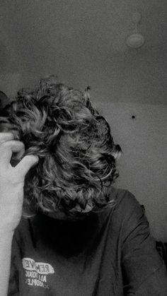 a woman with curly hair is talking on her cell phone while wearing a t - shirt