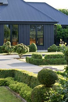 the house is surrounded by hedges and trees