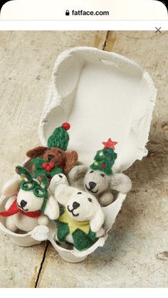 three stuffed animals are in an egg carton with christmas decorations on them and one is wearing a santa hat