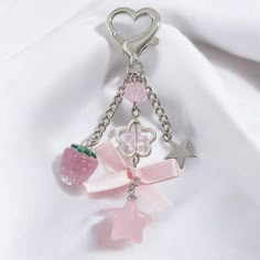 a key chain with charms attached to it on a white fabric background and a heart shaped object in the center