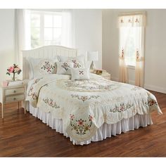 a white bed sitting on top of a wooden floor next to a dresser and window