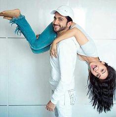 a man holding a woman on his back in front of a white wall with blue tiles