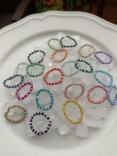 a white plate topped with lots of colorful bracelets on top of ice cubes