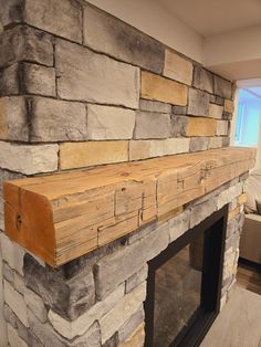 a stone fireplace in a living room with wood trimming on the mantel and mantle