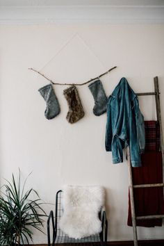 a room with a ladder, coat rack and two stockings hanging on the wall next to a potted plant