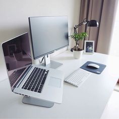 a laptop computer sitting on top of a white desk next to a monitor and keyboard