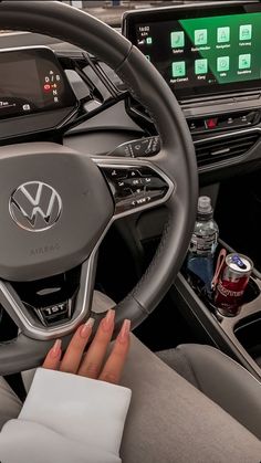 a woman driving a car with her hand on the steering wheel and an electronic screen