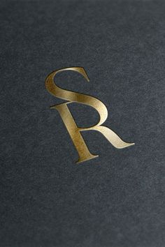 the letter r is made up of gold foil on a black surface with a silver background