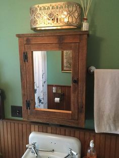 a bathroom sink sitting under a mirror in front of a wooden cabinet with lights on it