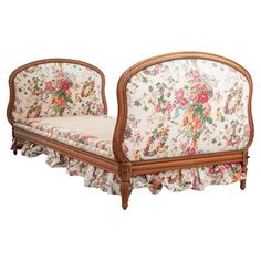 an old fashioned couch with floral fabric and wood trimming on the back, sitting in front of a white background