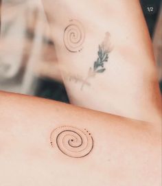 a woman's arm with two tattoos on it and one has a spiral design