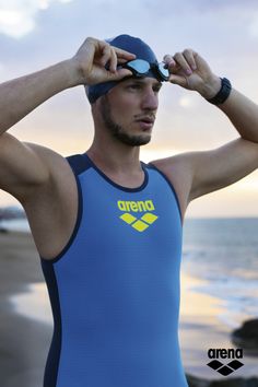 a man standing on the beach looking through his swimming cap