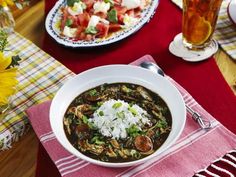 a bowl of soup on a table with flowers and plates of food in the background