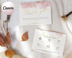 wedding stationery with gold foil lettering and pink watercolors on white paper, next to some dried leaves