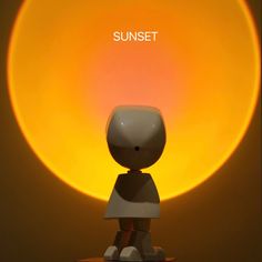 a small toy sitting on top of a table next to a yellow light that reads sunset