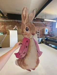 a person holding up a paper cut out of a rabbit