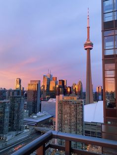 the city skyline is lit up at dusk with skyscrapers in the foreground and pink clouds in the sky