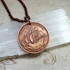 a penny is sitting on top of a piece of glass next to a beaded necklace